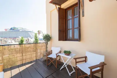 a balcony with a table and chairs and a cruise ship at Ladino Old Town in Rhodes Town