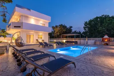 a villa with a swimming pool in front of a house at Villa Dana by Villa Plus in Ialyssos