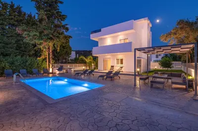 a villa with a swimming pool in front of a house at Villa Dana by Villa Plus in Ialyssos
