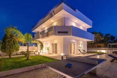 a large white house with a table in front of it at Villa Dana by Villa Plus in Ialyssos