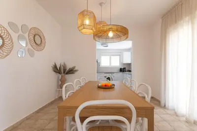 a dining room with a wooden table and white chairs at Villa Lavanda, panoramic view! in Kalathos
