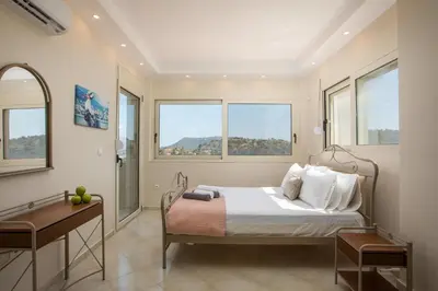a bedroom with a bed and a desk and windows at Escape In View Villa Rhodes in Pastida