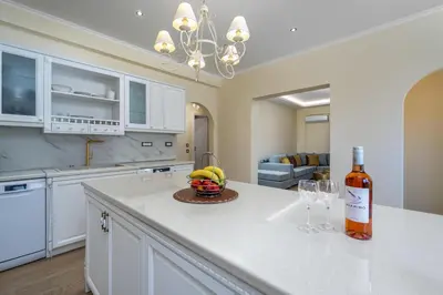 a bottle of wine and a bowl of fruit on a kitchen counter at J O House in Archangelos