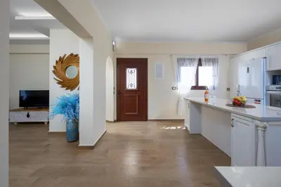 a kitchen with white cabinets and a wooden floor at J O House in Archangelos