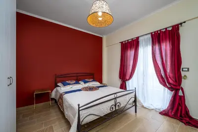 a bedroom with a bed with red walls and a window at J O House in Archangelos