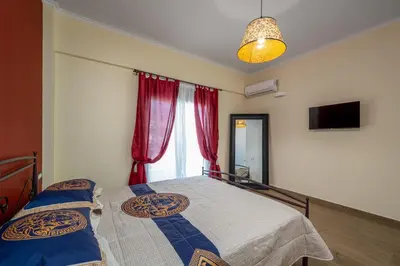 a bedroom with two beds and a window with red curtains at J O House in Archangelos