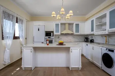 a kitchen with white cabinets and a large island at J O House in Archangelos