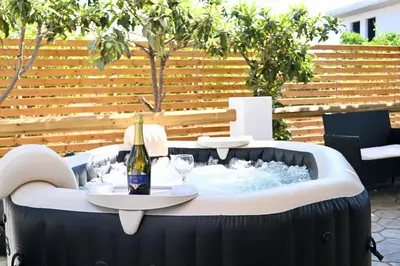 a hot tub with a bottle of wine and glasses at Harmony Garden House in Ialyssos