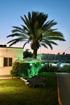 a table and chairs under an umbrella next to a palm tree at Harmony Garden House in Ialyssos