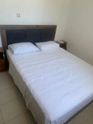 a large white bed with a blue headboard and white sheets at KakLeCharaki in Haraki