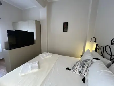 a bedroom with a white bed with a flat screen tv at Mirodaty's House in Rhodes Town