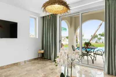 a living room with a television and a table with chairs at Le Palme Beach Rhodes in Haraki