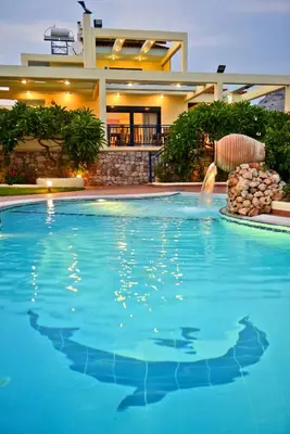 a swimming pool with a fountain in front of a house at Villa Angelina in Pefki Rhodes