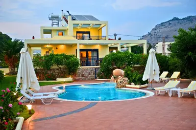 a villa with a swimming pool in front of a house at Villa Angelina in Pefki Rhodes