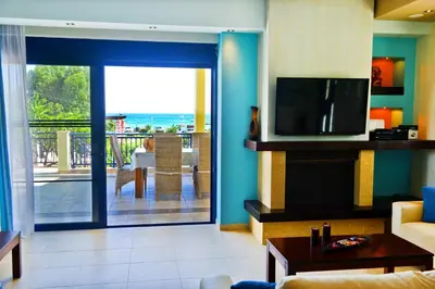 a living room with a couch and a television and a balcony at Villa Angelina in Pefki Rhodes