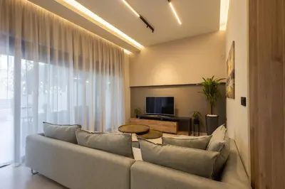 a living room with a couch and a tv at Kallithea Blue in Koskinou