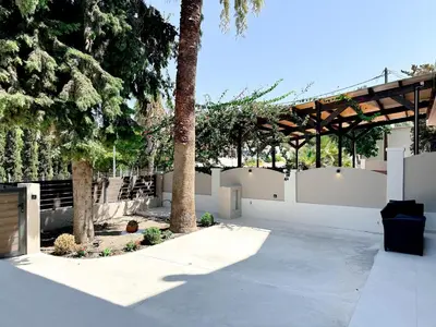 a courtyard with a white fence and trees at Kallithea Blue in Koskinou