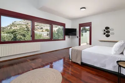 a bedroom with a bed and a tv and two windows at Villa Olive in Koskinou