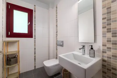 a white bathroom with a sink and a toilet at Villa Olive in Koskinou
