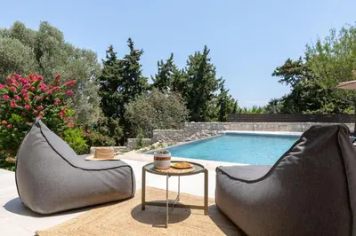 two chairs and a table next to a swimming pool at Villa Olive in Koskinou
