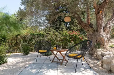 two chairs and a table in front of a tree at Villa Olive in Koskinou