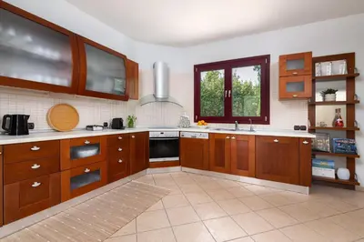 a large kitchen with wooden cabinets and a window at Villa Olive in Koskinou