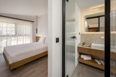 a bedroom with a bed and a sink and a mirror at Alma Luxury Villas in Ialyssos