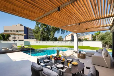 a patio with a table and chairs and a swimming pool at Alma Luxury Villas in Ialyssos