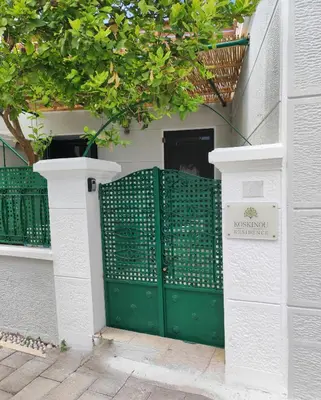 a green door in a white building with a sign at Koskinou Residence in Koskinou