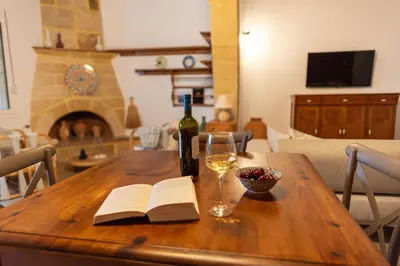 a wooden table with a bottle of wine and a wine glass at La Casa di Varvara e Nikolas in Soroni