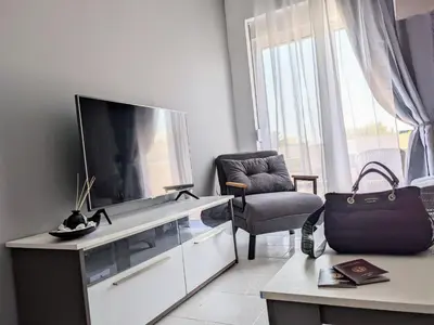 a living room with a large television and a chair at Mini Mansion in Rhodes Town