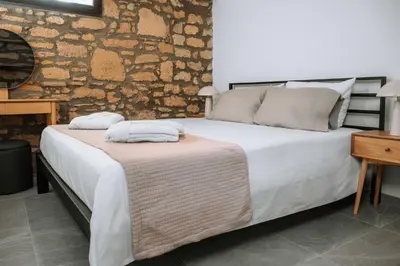 a bedroom with a large bed with a stone wall at Manolis Seaside Villa in Soroni