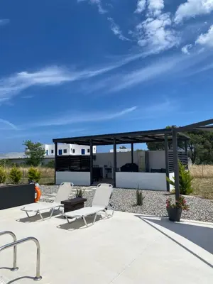 a patio with two white chairs and a pavilion at Vigla Kiotari in Kiotari