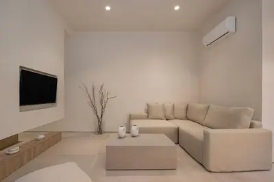 a white living room with a couch and a tv at Natural Harmony ,Luxury Studio Oasis & Hot Tub in Rhodes Town