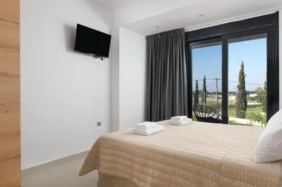 a bedroom with a bed and a large window at Davlakos Villa Eve in Kremasti
