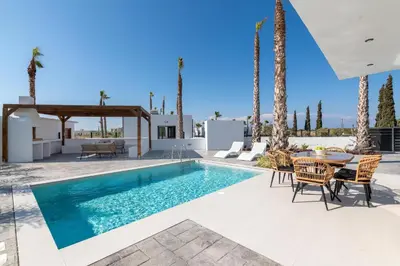 a pool with a table and chairs and palm trees at Davlakos Villa Eve in Kremasti
