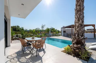 a patio with a table and chairs next to a pool at Davlakos Villa Eve in Kremasti