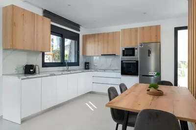 a kitchen with white cabinets and a wooden table at Davlakos Villa Eve in Kremasti