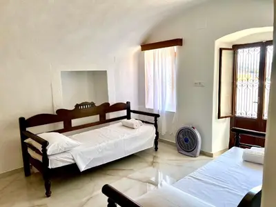 a bedroom with two beds and a large window at Symi Roots House in Symi
