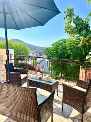 a patio with chairs and a table and an umbrella at Symi Roots House in Symi