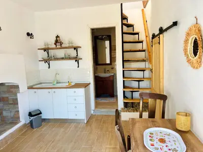 a kitchen and dining room with a table and a staircase at Symi Roots House in Symi