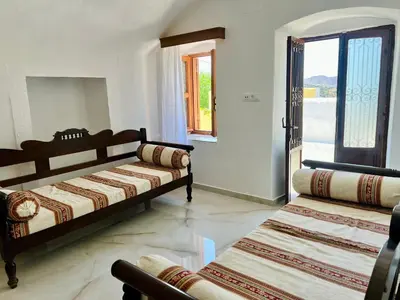 a bedroom with two beds and a door to a balcony at Symi Roots House in Symi