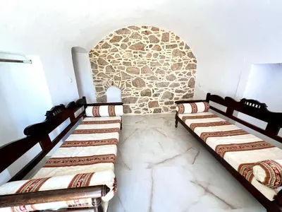 a room with three beds and a stone wall at Symi Roots House in Symi