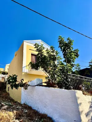 a yellow house with a staircase in front of it at Symi Roots House in Symi
