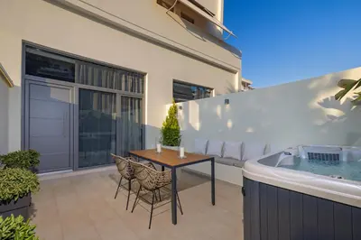 a patio with a table and chairs next to a bath tub at Earthy Haven-Minimalist Luxury Studio & Hot Tub in Rhodes Town