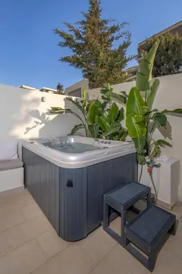 a jacuzzi tub on a balcony with a stool at Earthy Haven-Minimalist Luxury Studio & Hot Tub in Rhodes Town