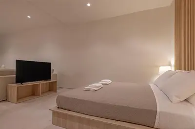 a bedroom with a bed and a flat screen tv at Earthy Haven-Minimalist Luxury Studio & Hot Tub in Rhodes Town