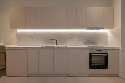 a kitchen with white cabinets and a sink at Earthy Haven-Minimalist Luxury Studio & Hot Tub in Rhodes Town