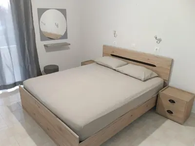 a bed with a wooden headboard in a bedroom at Helene Mirteni in Ialyssos