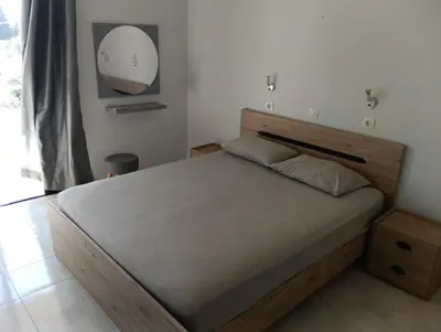 a bedroom with a bed with a wooden headboard and a mirror at Helene Mirteni in Ialyssos